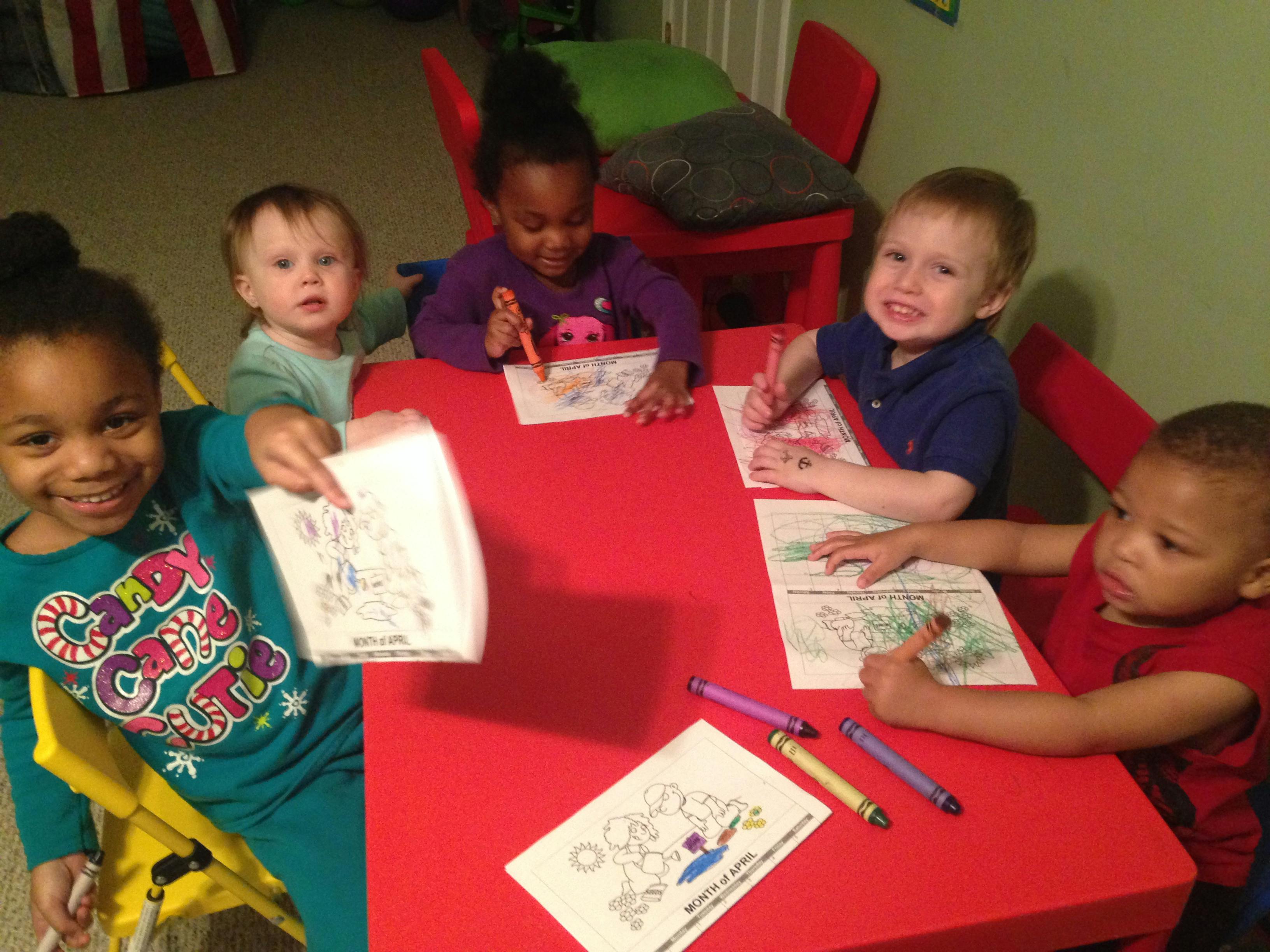Four children coloring at a red table