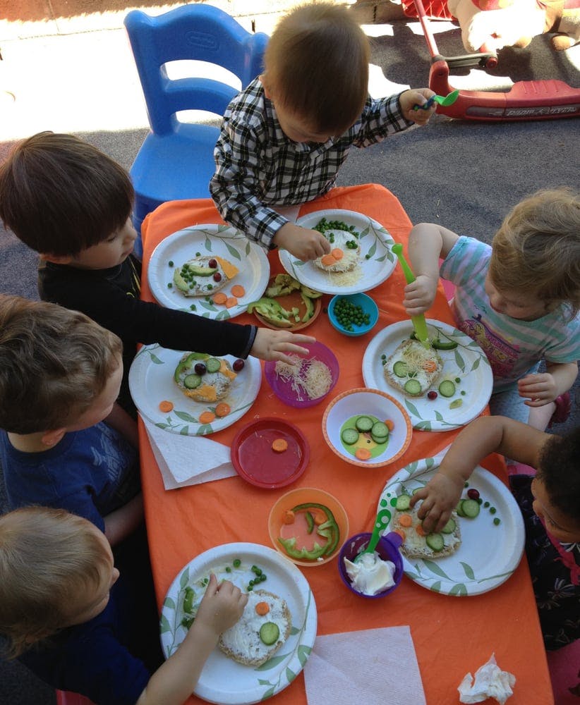 Children decorating food on plates at a table