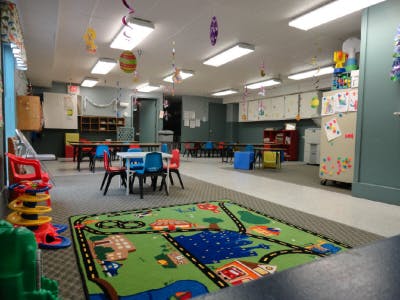 Classroom with small tables and chairs, and a play rug with a road map design