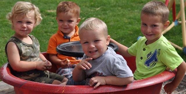 Four children sitting in a red wagon