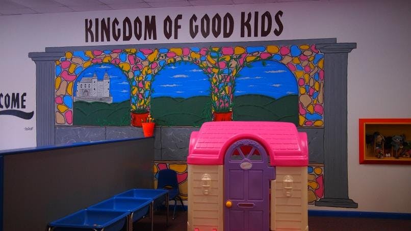 Playhouse and mural with text "KINGDOM OF GOOD KIDS"