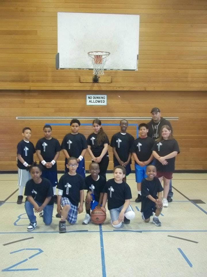Group of children and adults posing on a basketball court
