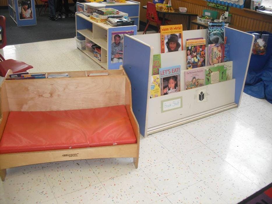 bench with red cushion next to a children's book shelf
