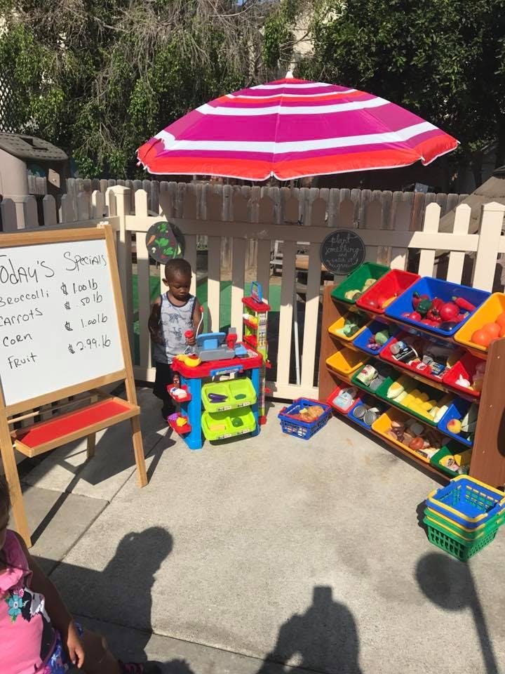 Child playing with a toy kitchen set outdoors