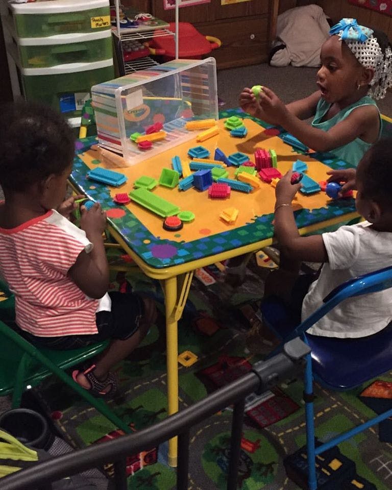 Three children playing with colorful blocks at a small table