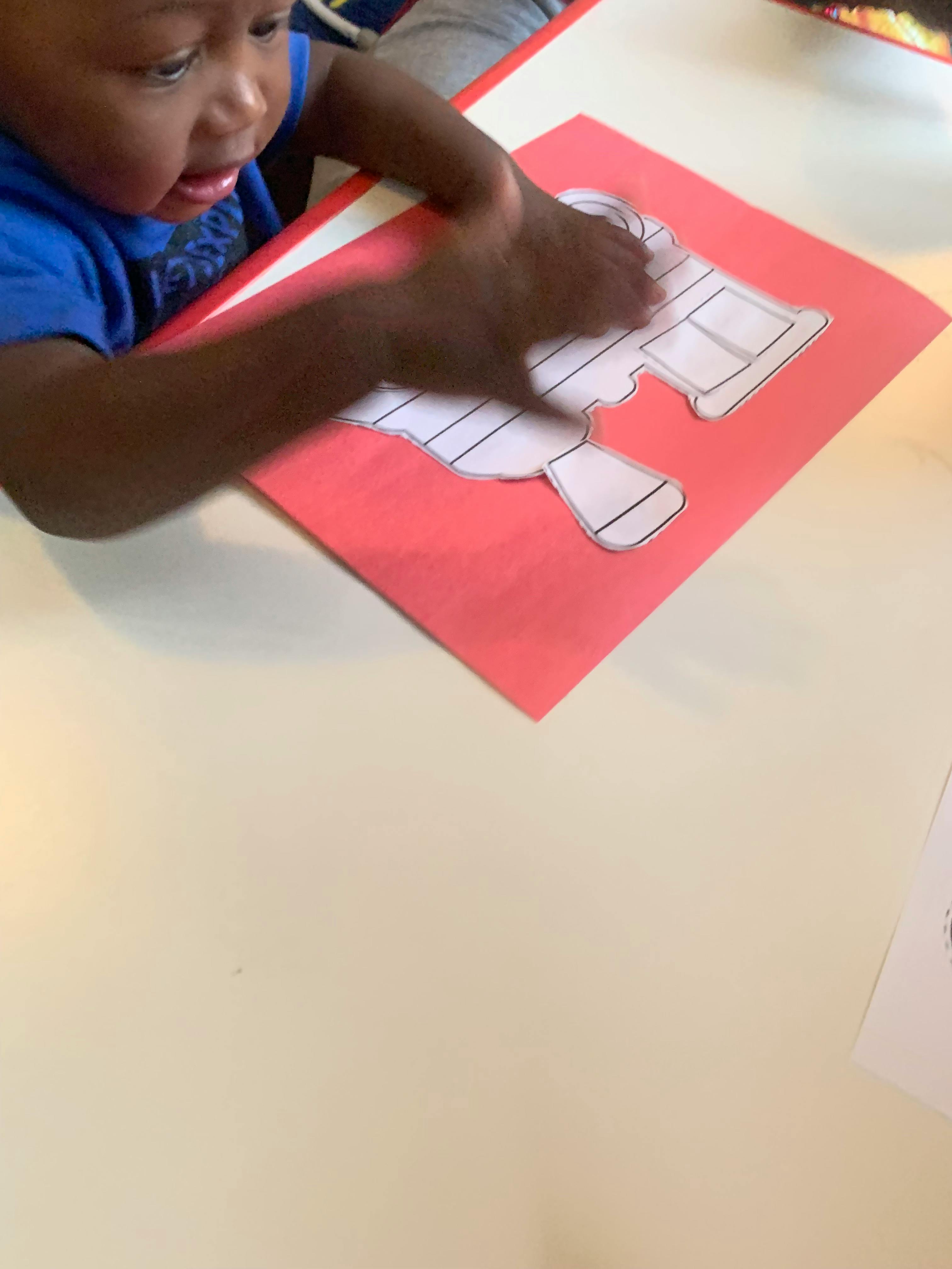 Child with hands on a paper cutout on a red sheet