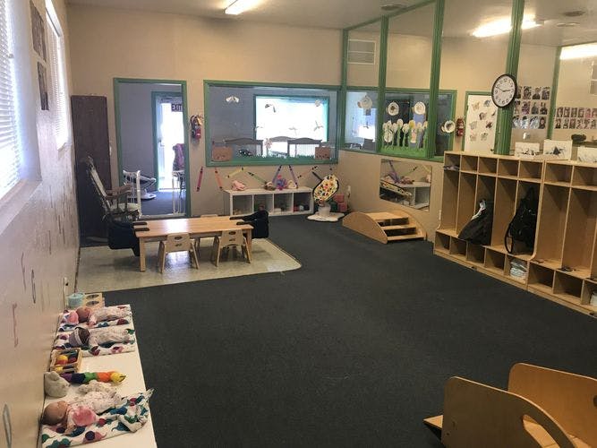 Empty classroom with small tables, chairs, and cubbies