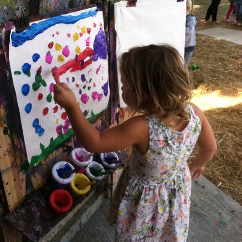 Child painting on an easel with various colors