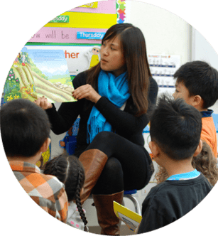 Person reading a book to children in a classroom