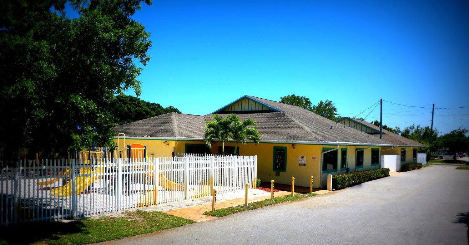 Yellow building with a white fence and playground equipment