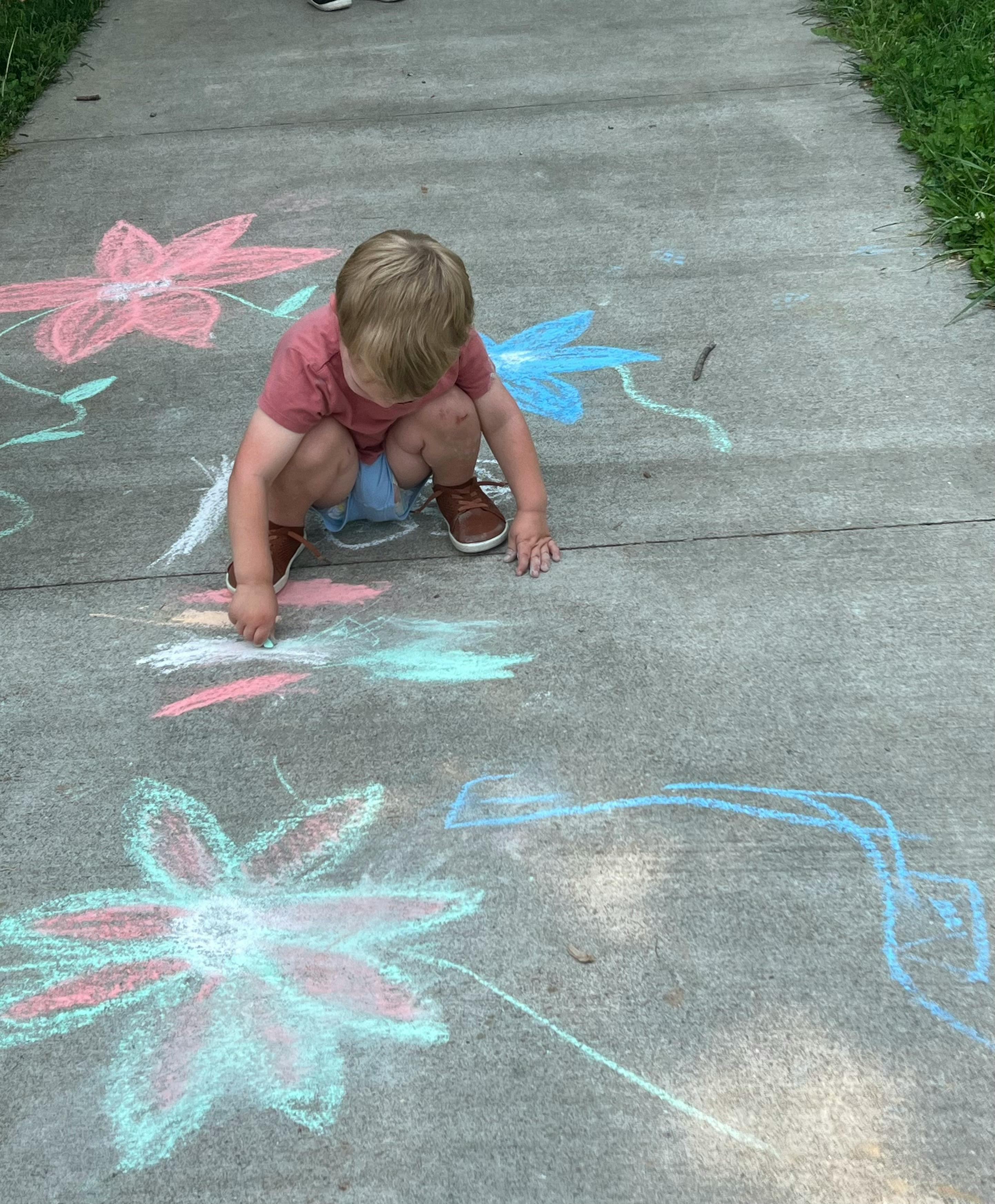 Child drawing with chalk on a sidewalk