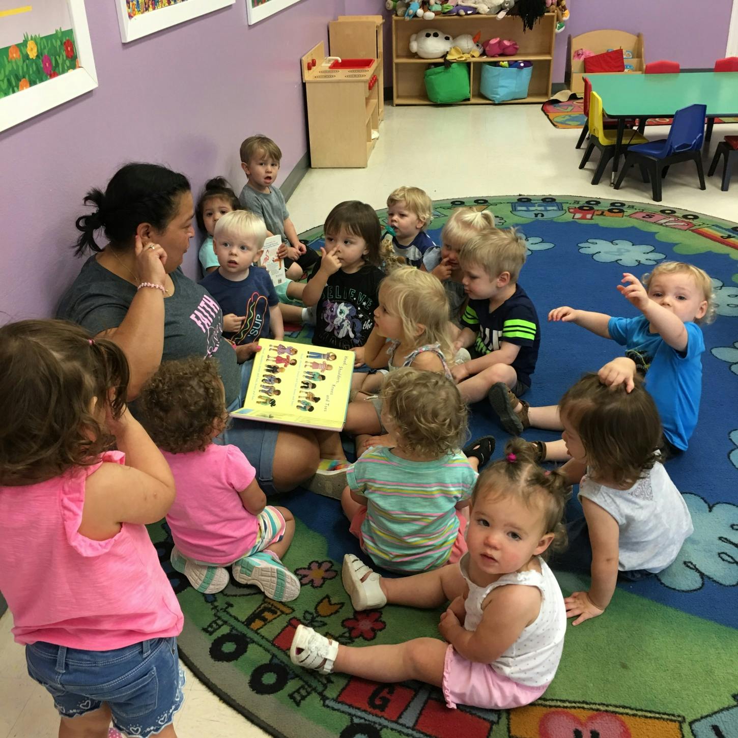 Adult reading a book to a group of children in a classroom