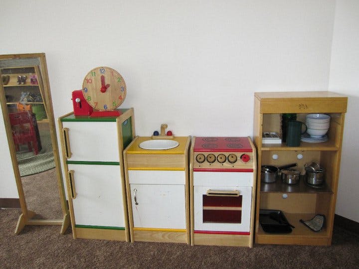 Children's play kitchen set with a mirror, refrigerator, sink, stove, and shelves