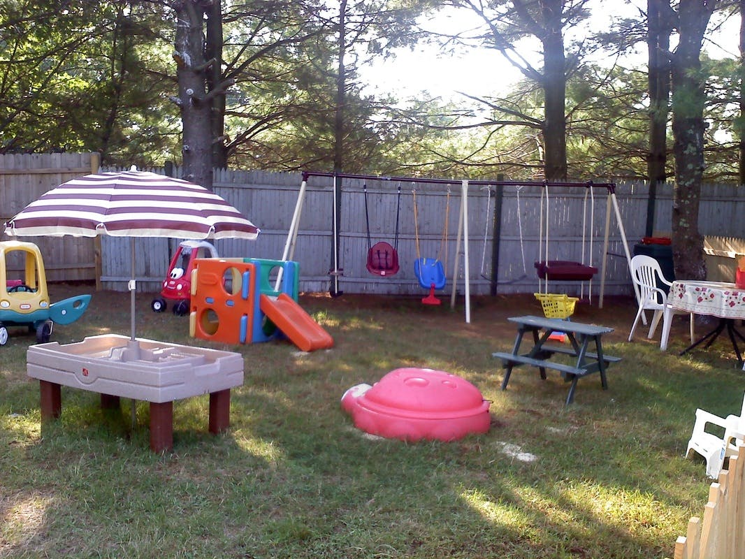 Outdoor playground with swings, slide, sand table, and picnic table