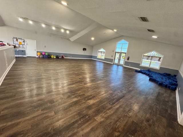 Empty open room with wood floor and windows