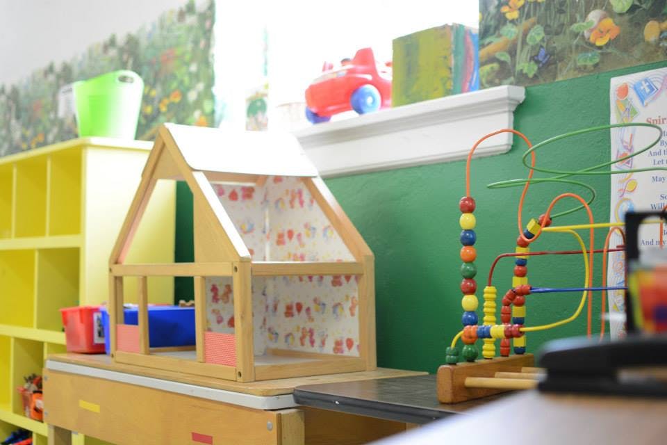 Wooden dollhouse and bead maze toy in a playroom