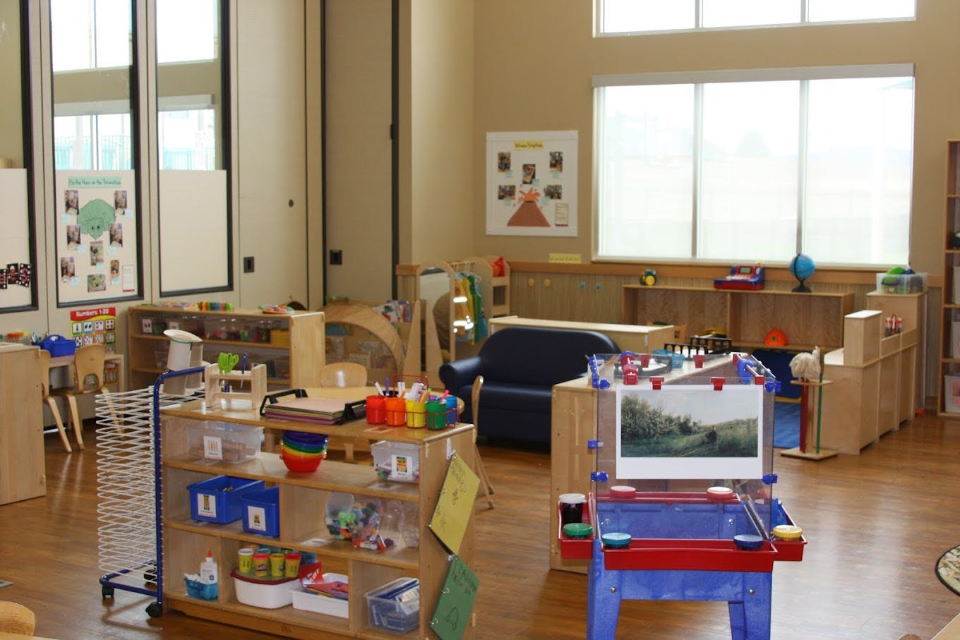 Children's classroom with an easel, shelves of toys, and a blue sofa