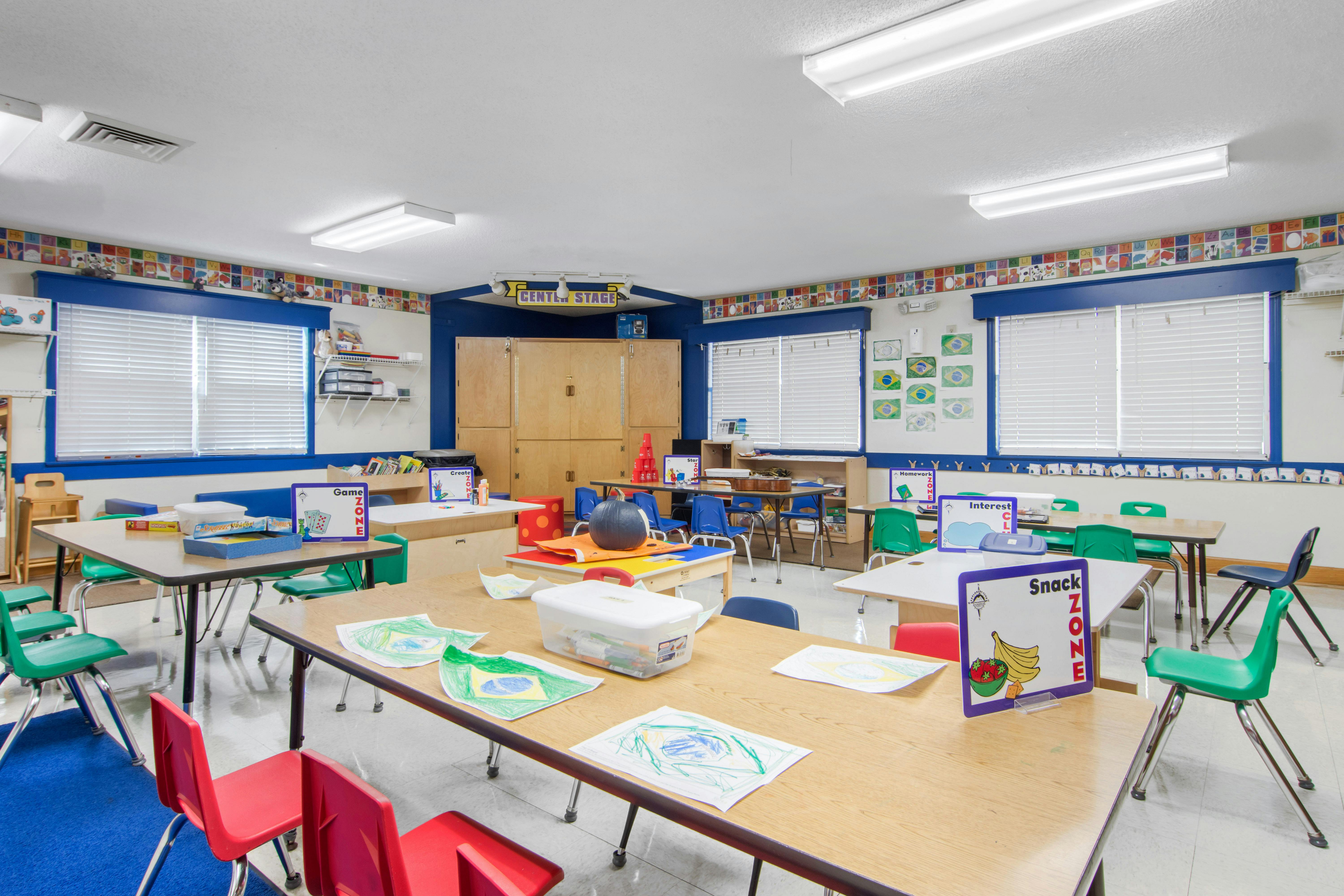 Classroom with child-sized tables and chairs, artwork on walls and tables