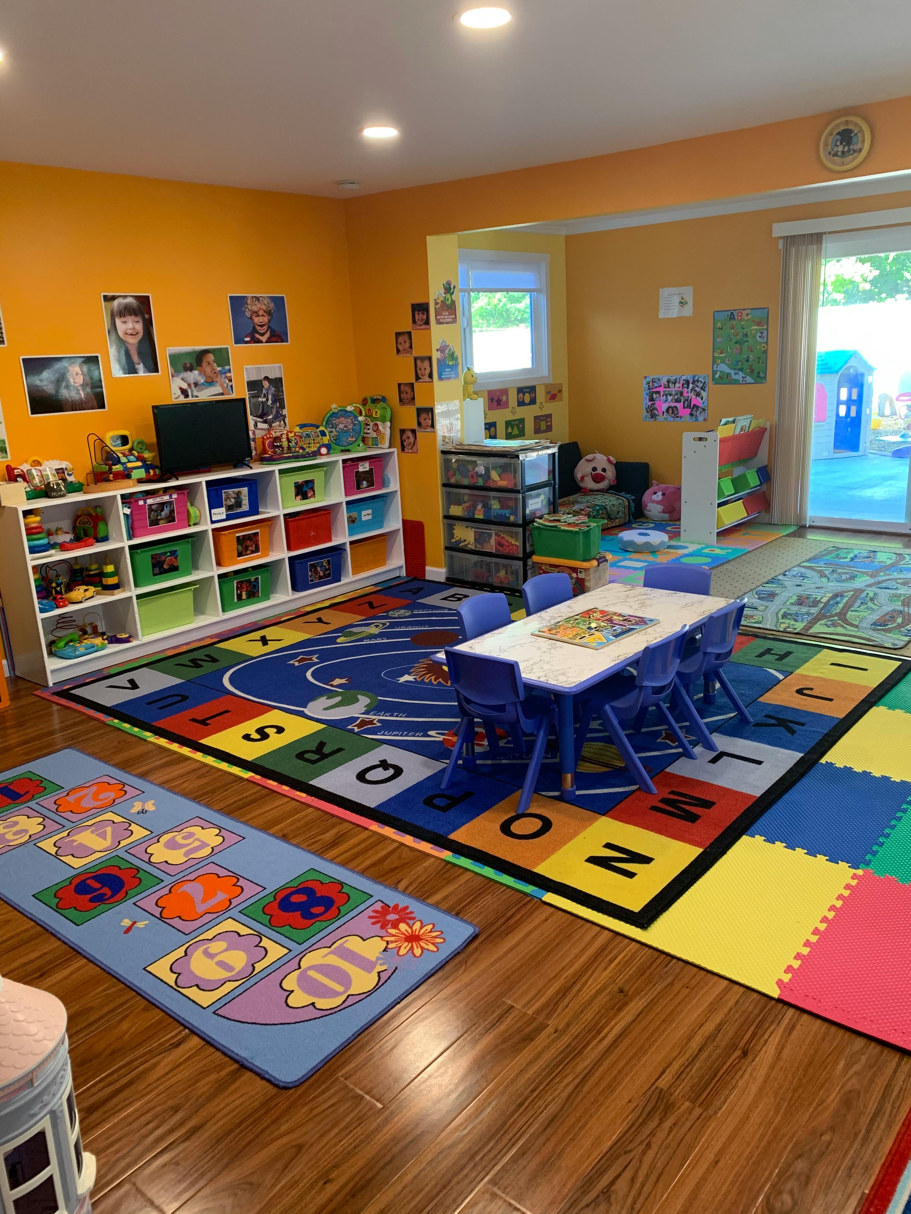 Playroom with colorful rugs, small table and chairs, and storage shelves