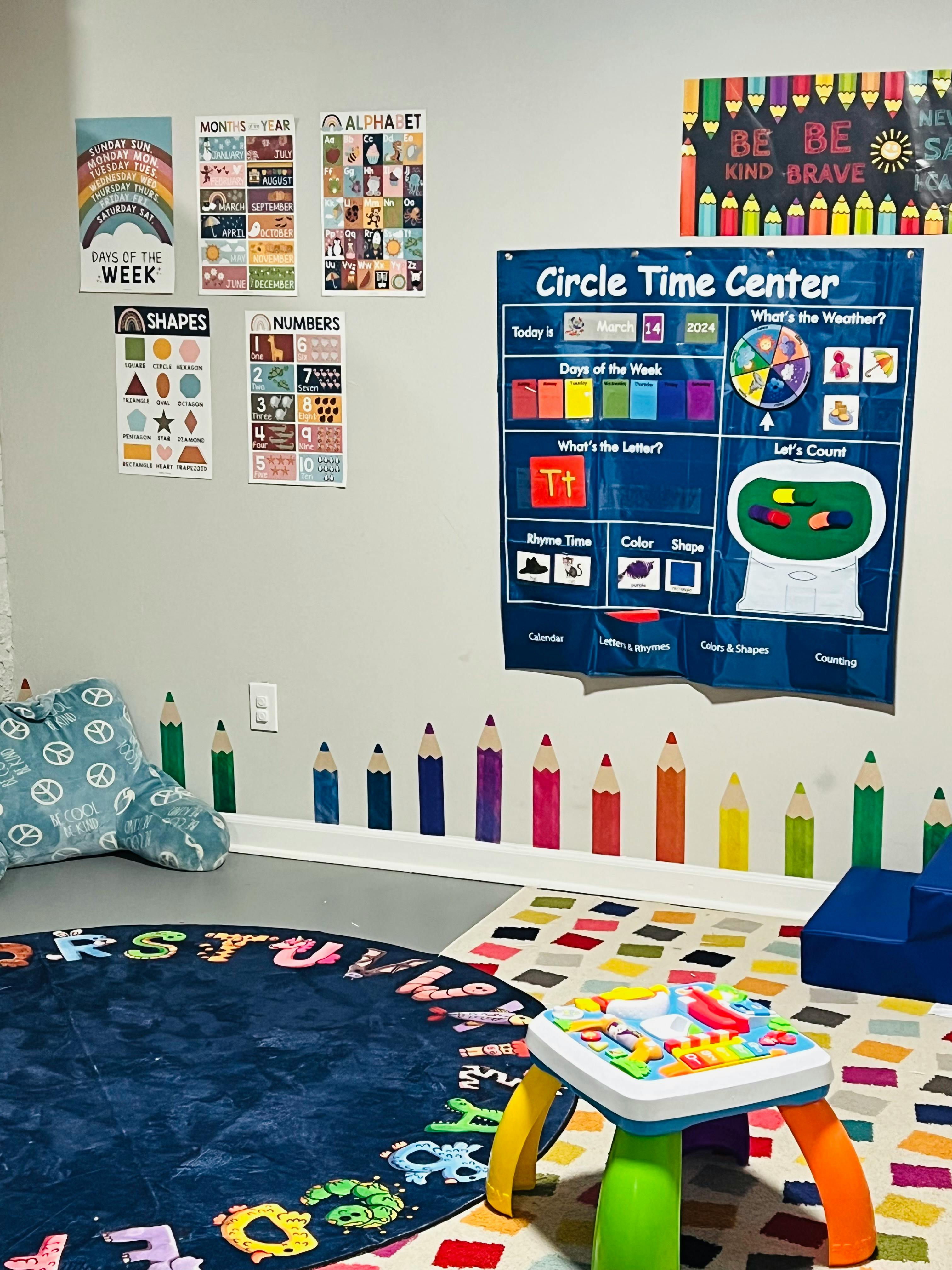 Classroom wall with educational posters and a colorful rug with alphabet letters
