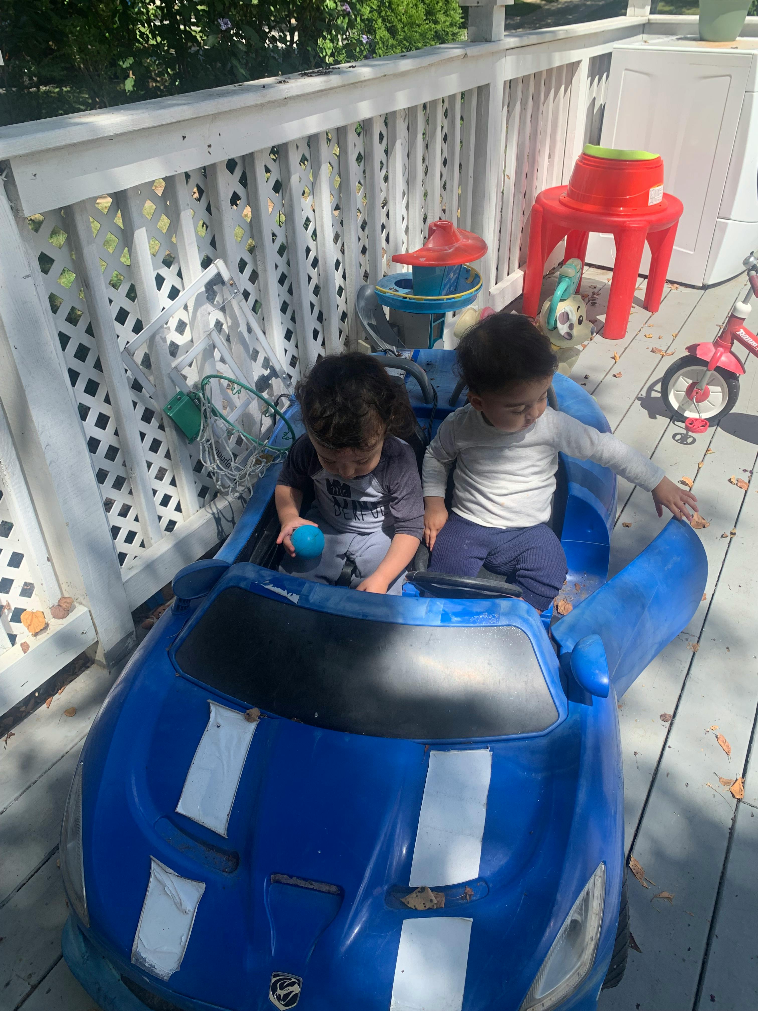 Two children sitting in a blue toy car