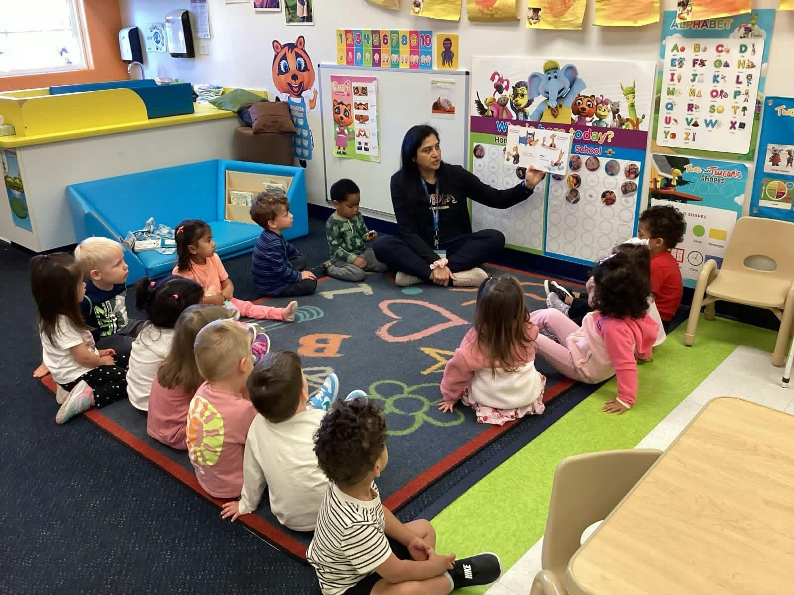 Teacher reading a book to a group of children sitting on a rug in a classroom