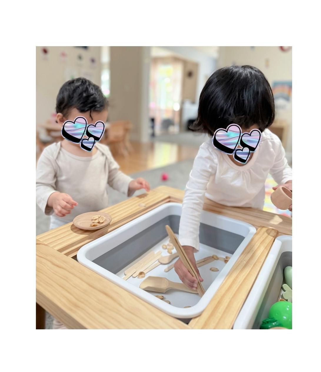 Two children playing at a sensory table with wooden toys