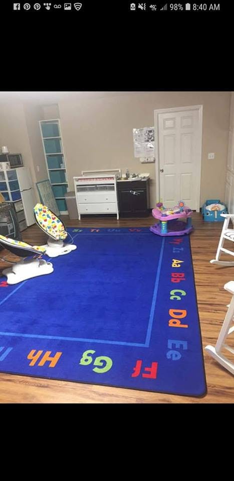 Blue alphabet rug in a room with baby items