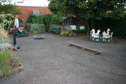 Outdoor play area with a small trampoline, basketball hoop, and carousel ride-on toy