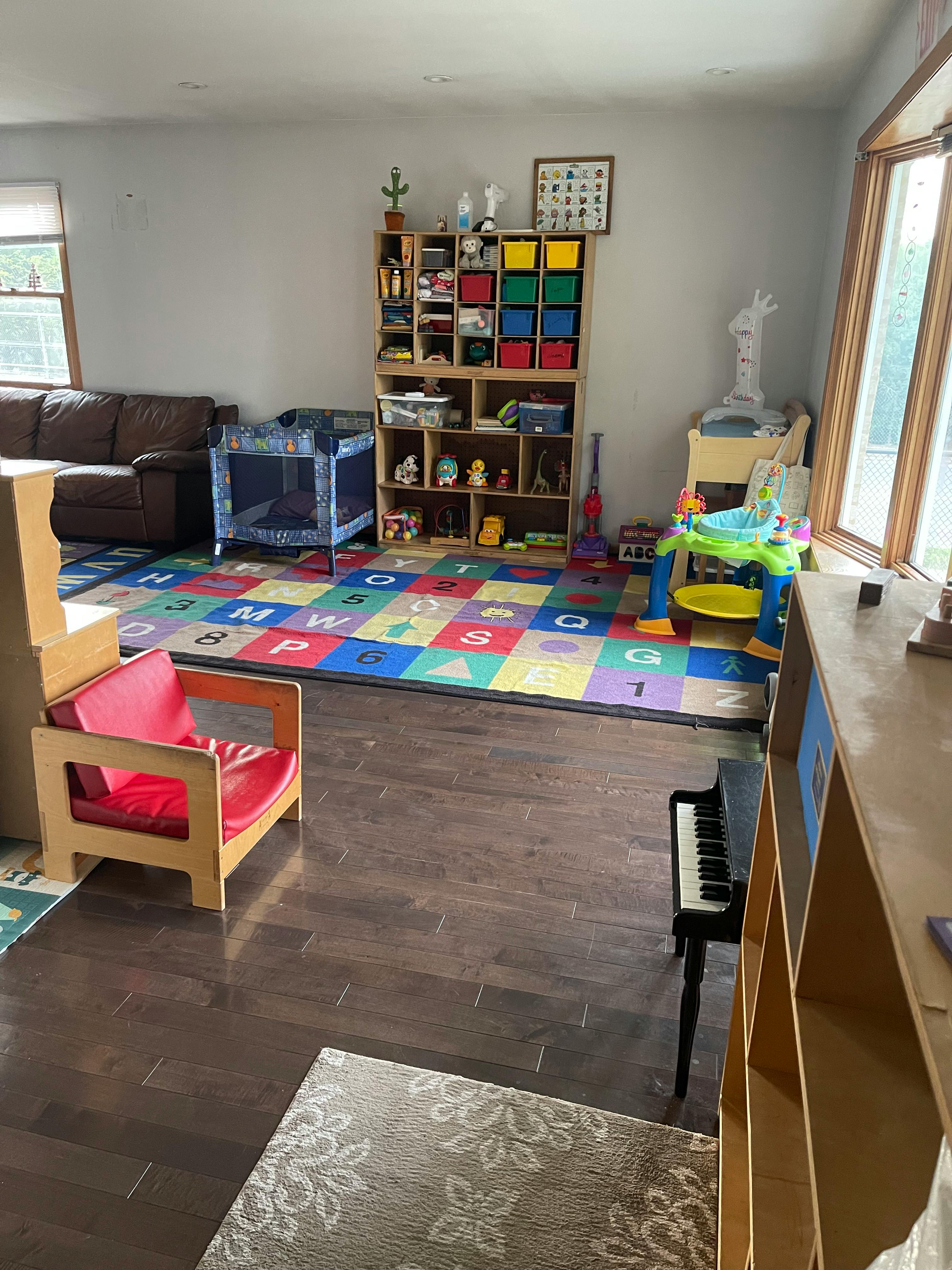 Playroom with alphabet rug, toy shelves, crib, and child's chair