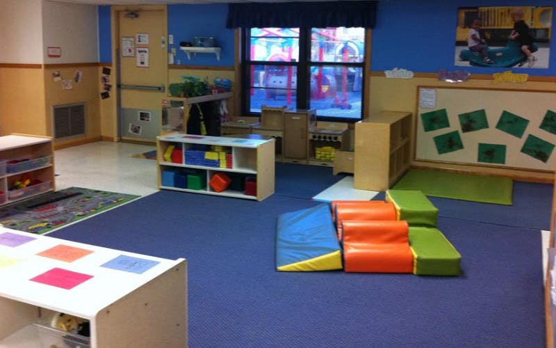 An empty daycare room with play equipment and a window looking out to a playground