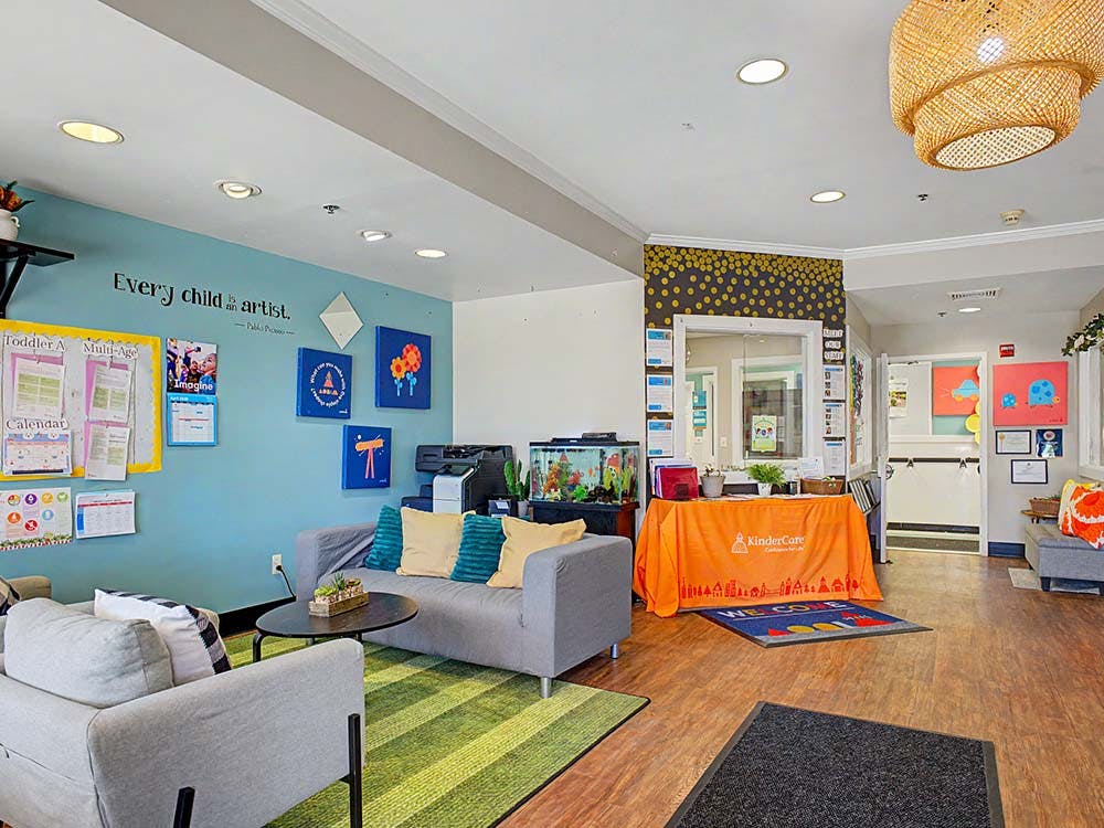 waiting area with sofas, a colorful rug, a bulletin board, and a reception desk