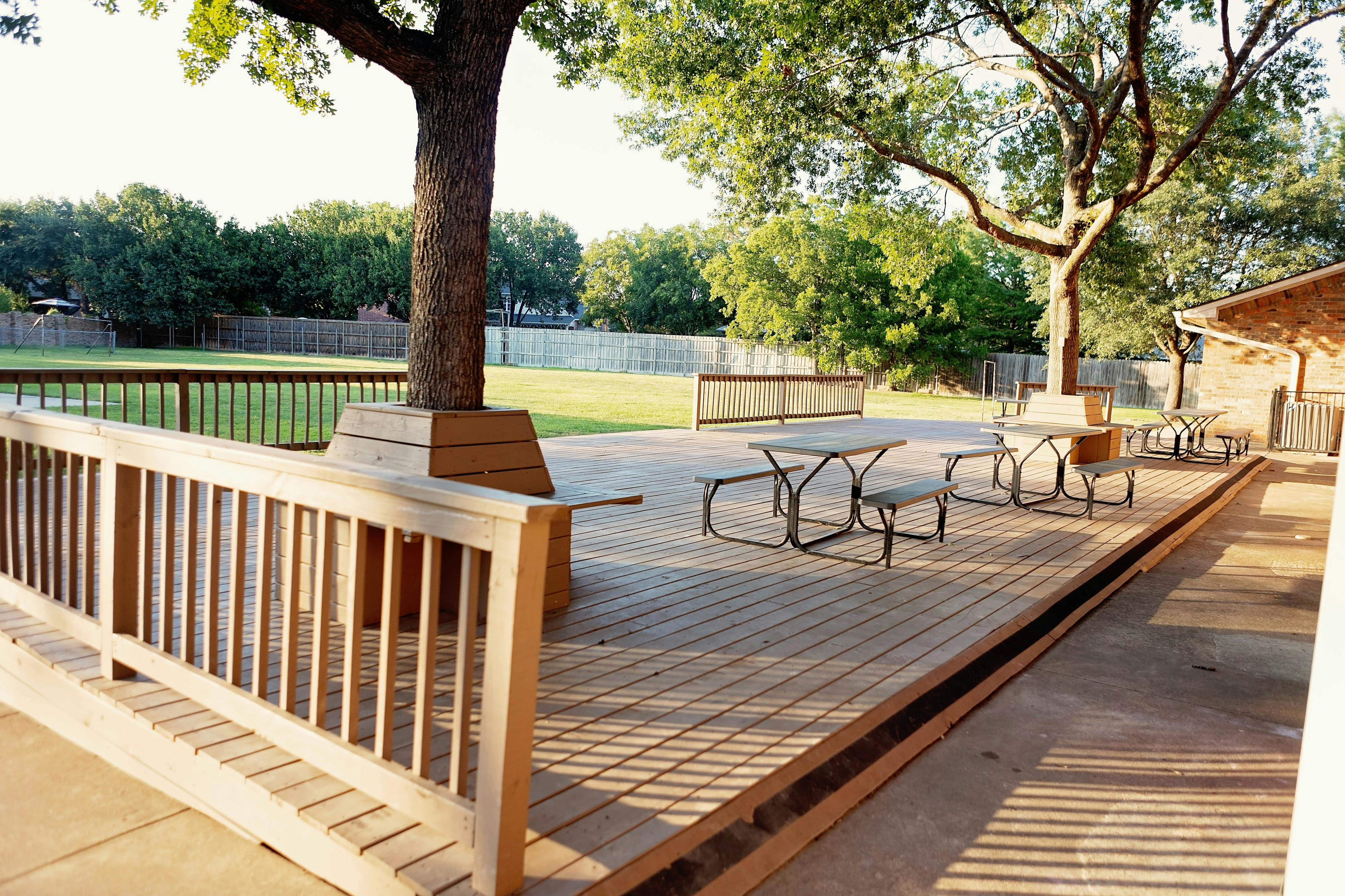 Outdoor wooden deck with picnic tables and a tree growing through it