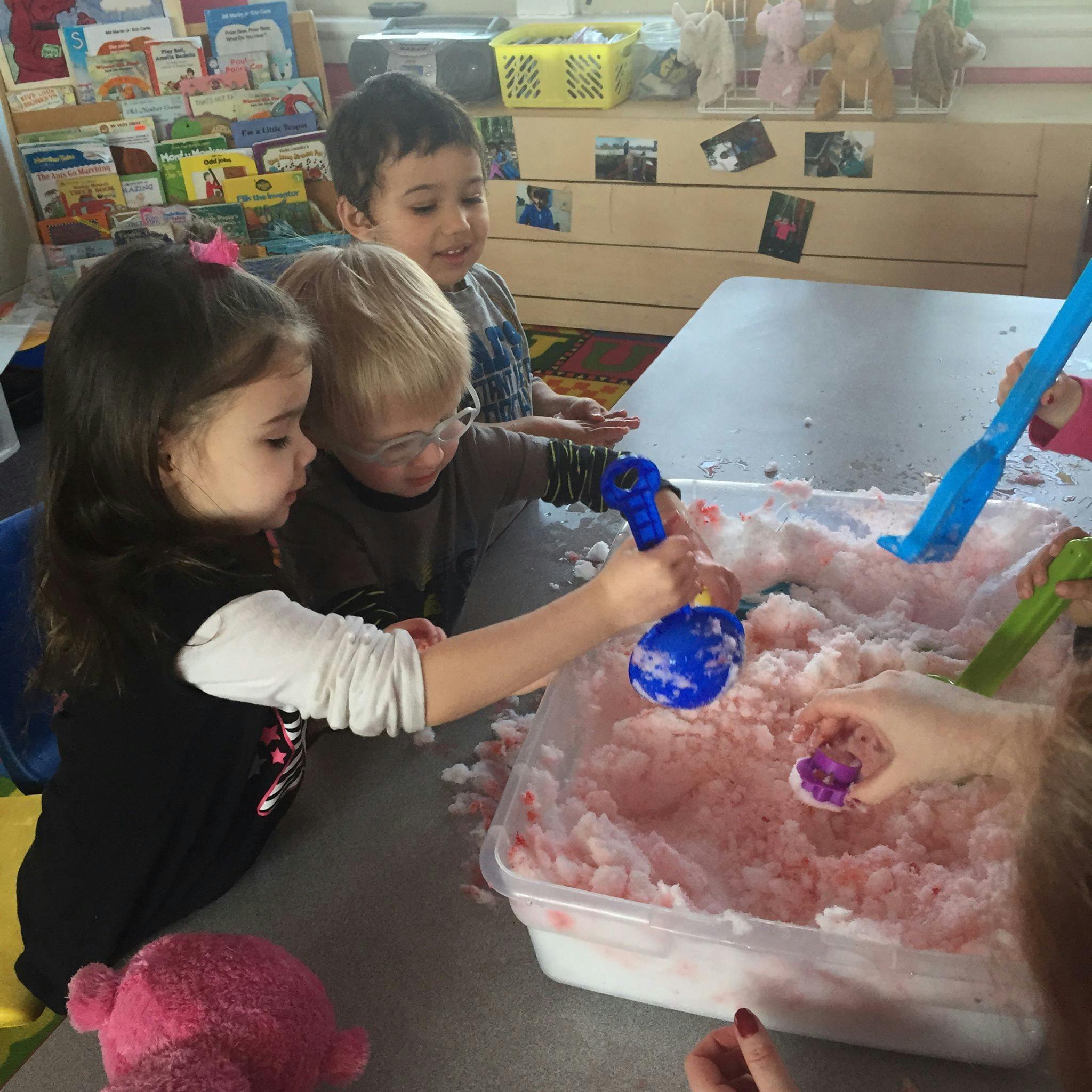 Children playing with pink sensory bin filler and scoops