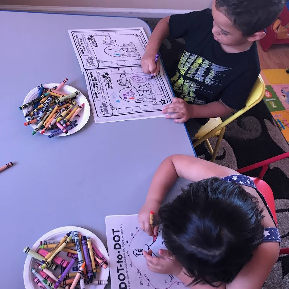 Two children coloring at a table with crayons