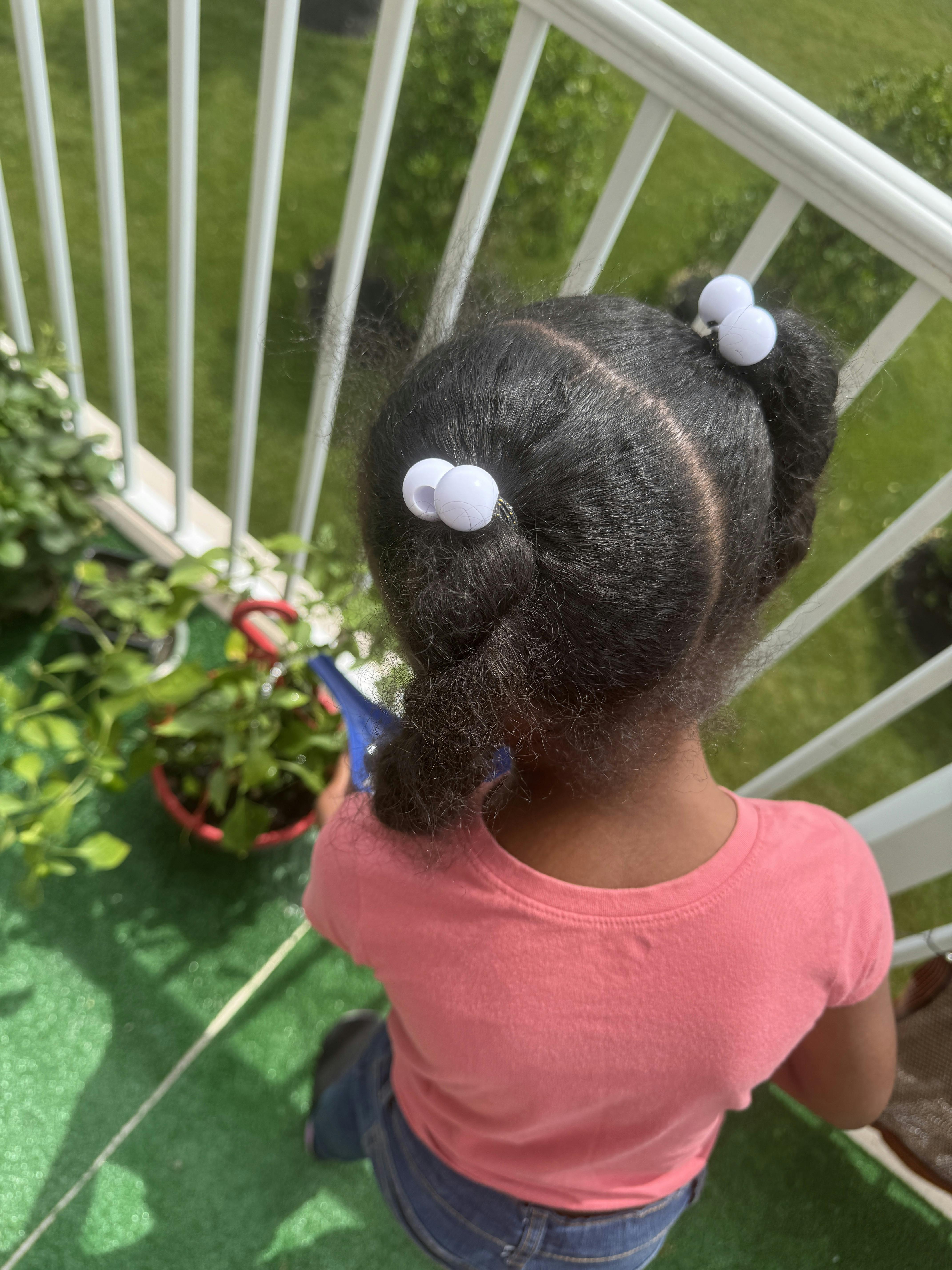 Child watering a plant on a balcony