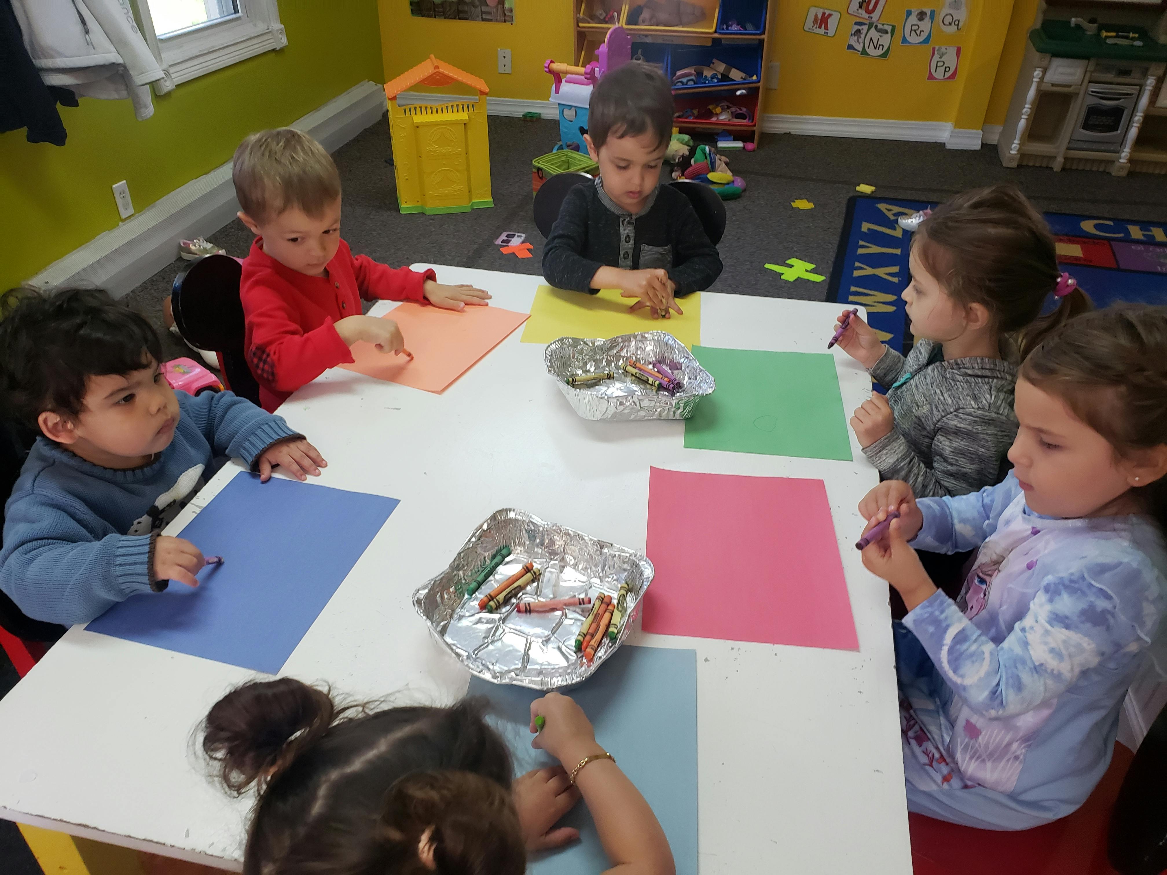Children sitting at a table with paper and crayons