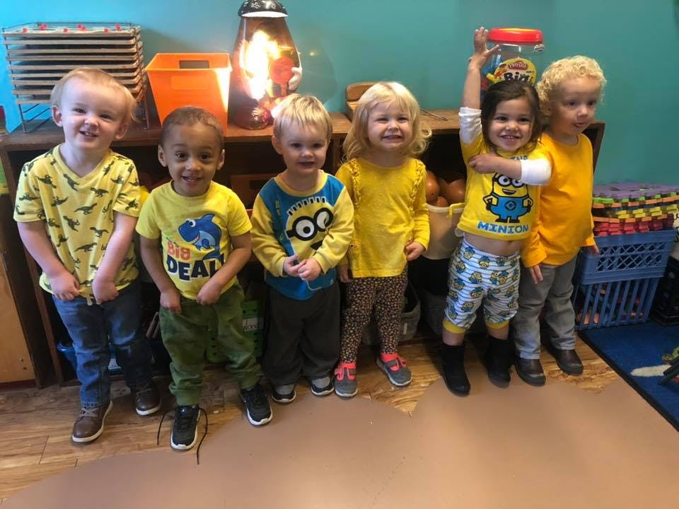 Group of children standing together, one child holding a jar