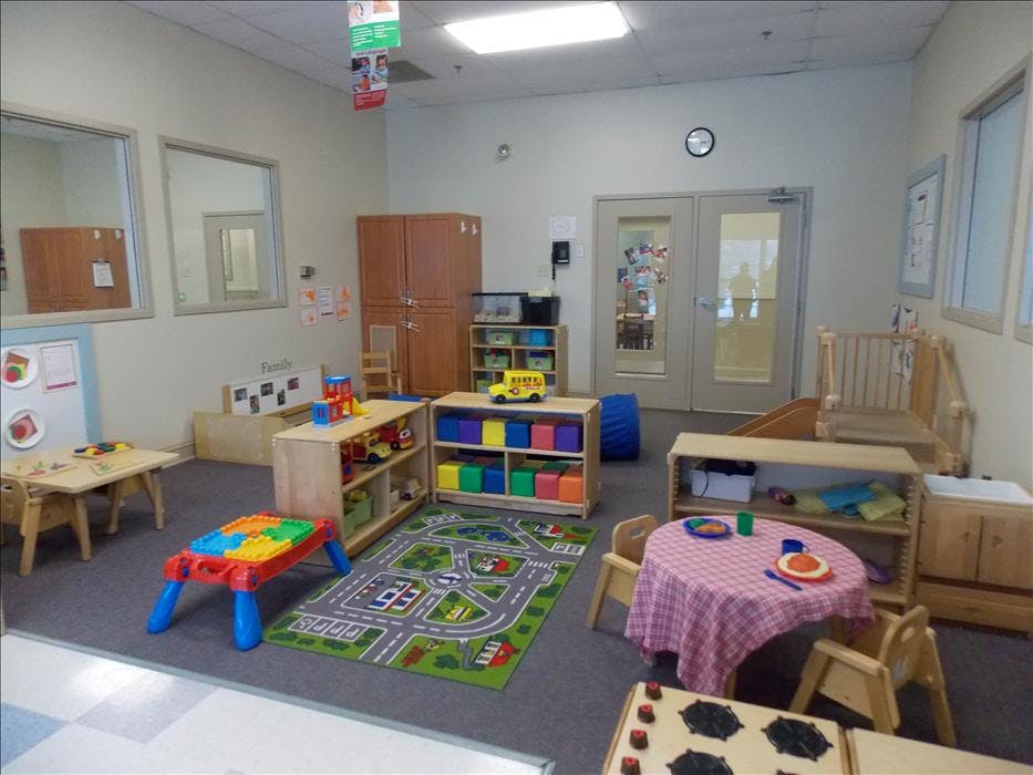 A colorful childcare classroom with toys, tables, and play areas