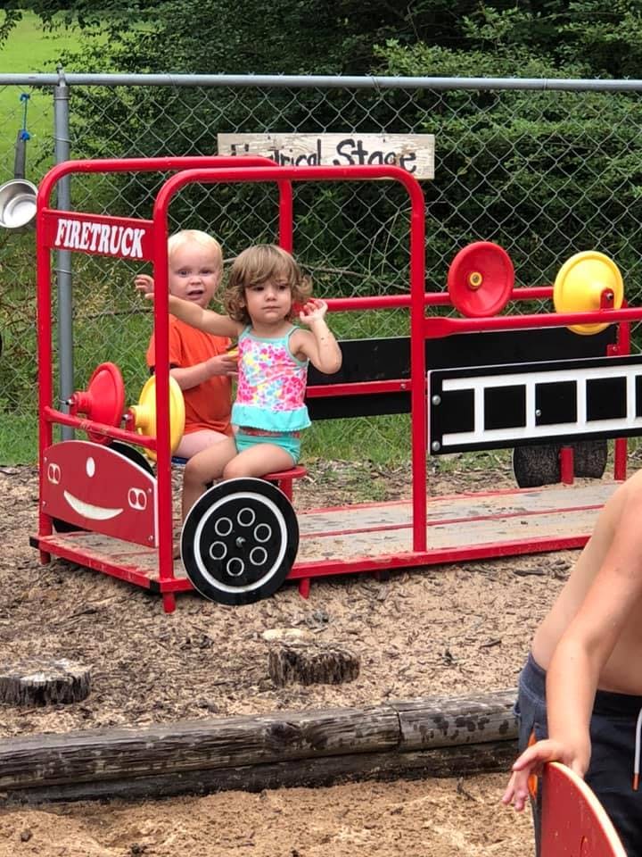 Two children sitting in a red play firetruck