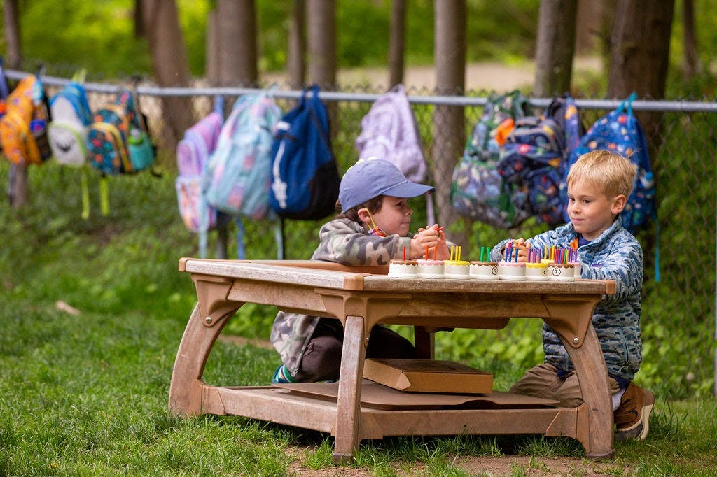Two children playing with colorful pegs at a small table outdoors