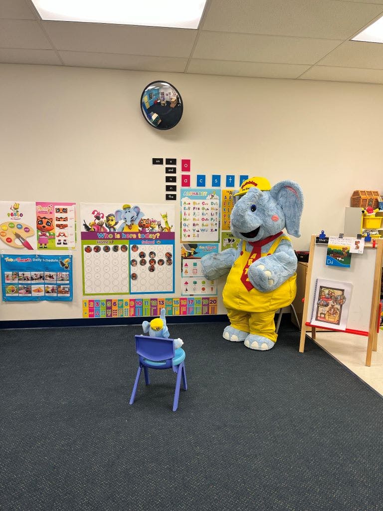 Elephant mascot in a classroom with a small chair and stuffed animal
