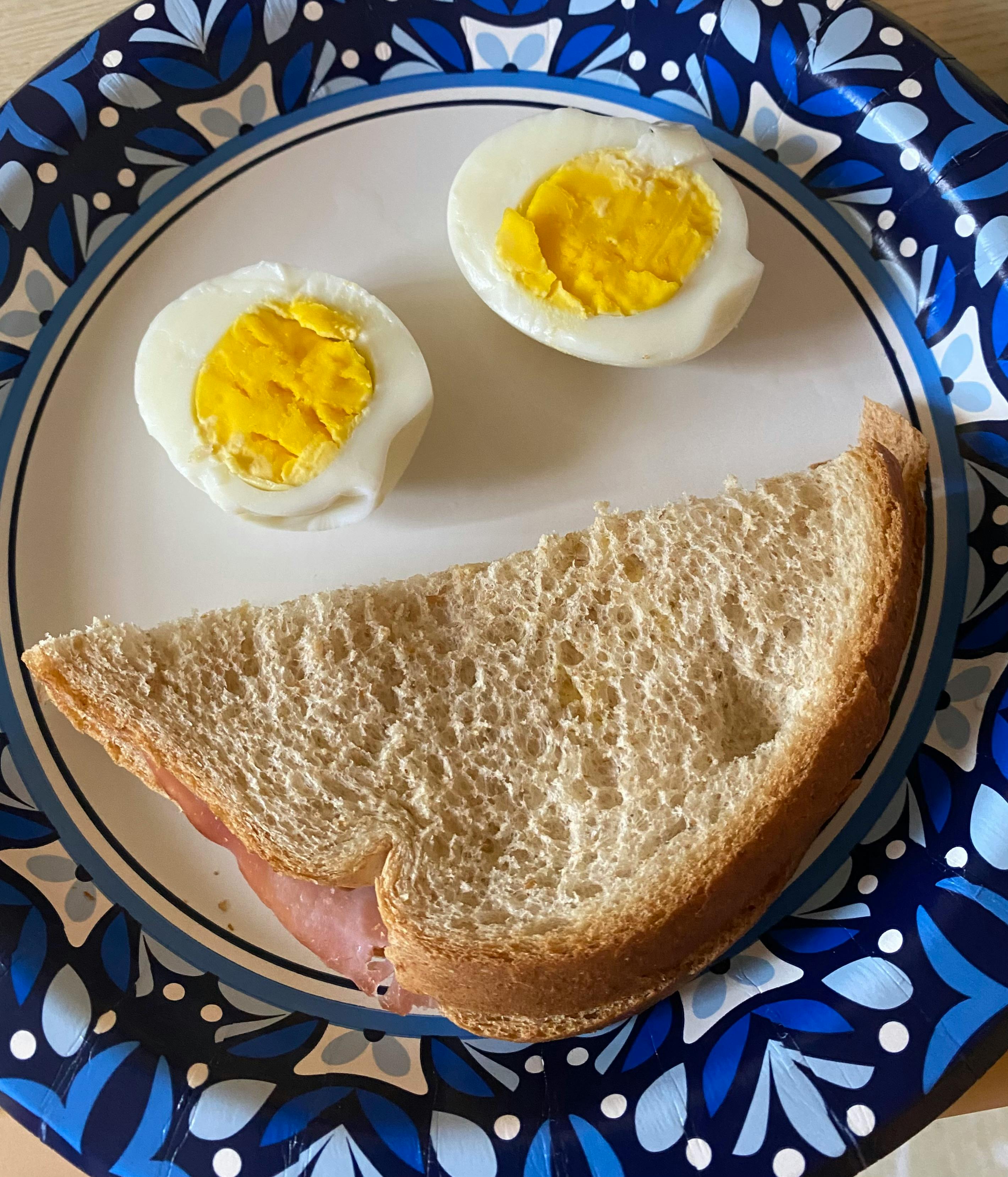 A sandwich and two hard-boiled egg halves on a plate
