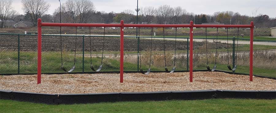 Red swing set with multiple swings over wood chips