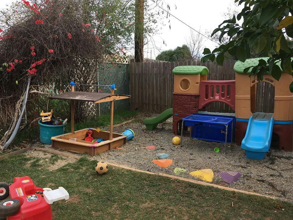 Outdoor play area with a sandbox and a plastic play structure with slides