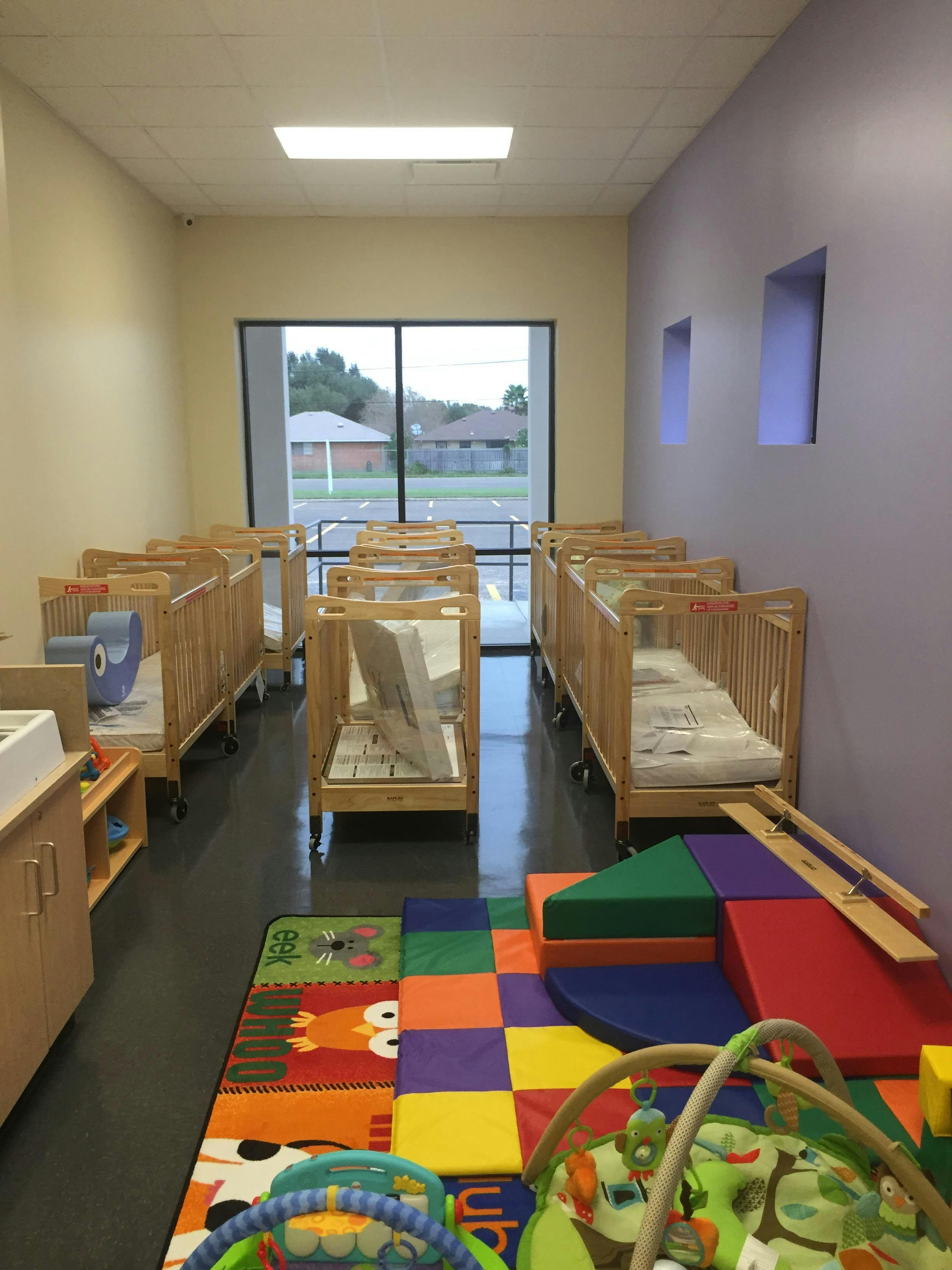 Room with multiple cribs and colorful play mats
