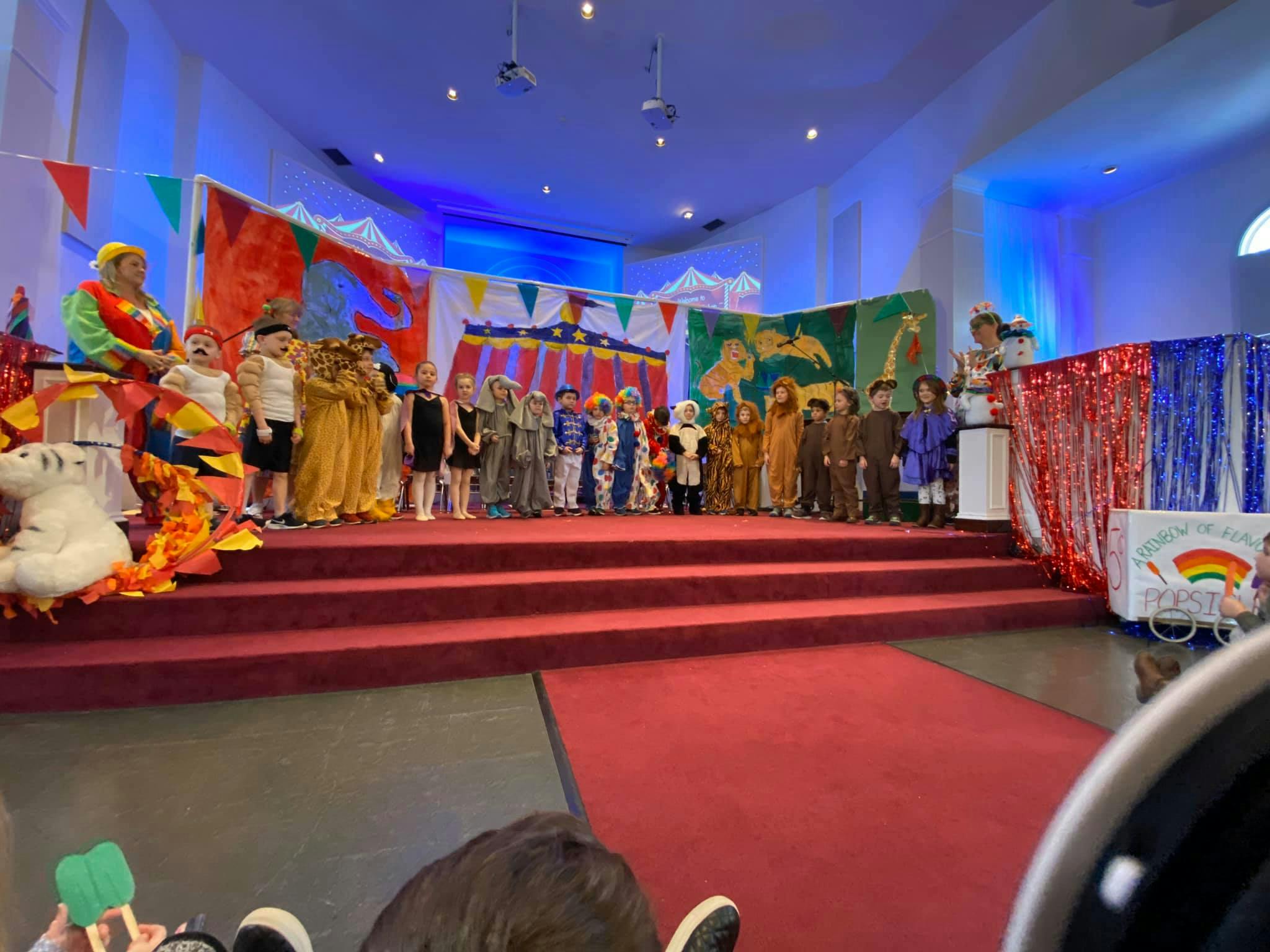 Children in costumes on a stage with a person dressed as a clown