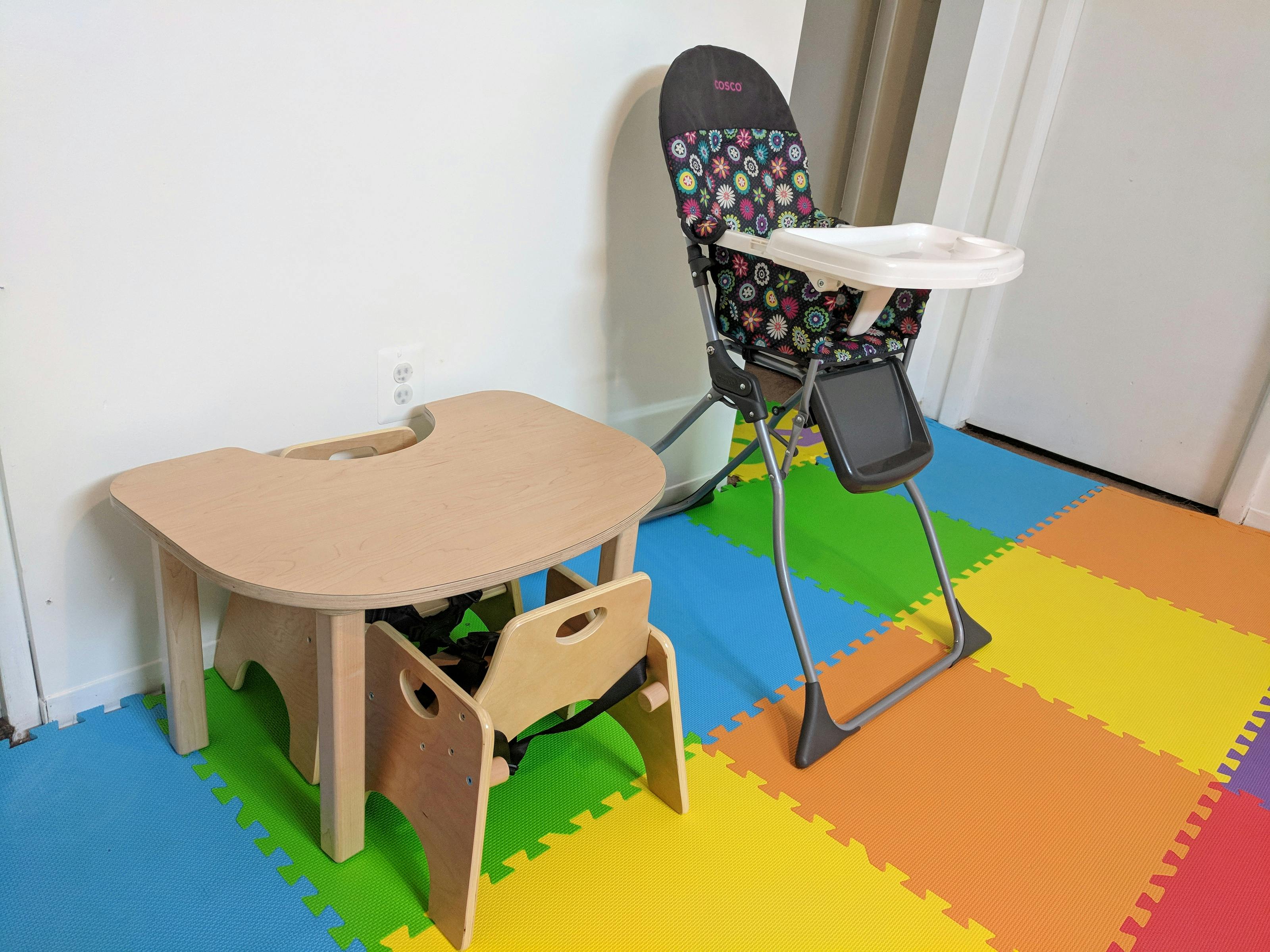 Child's table with chair and high chair on a colorful foam mat