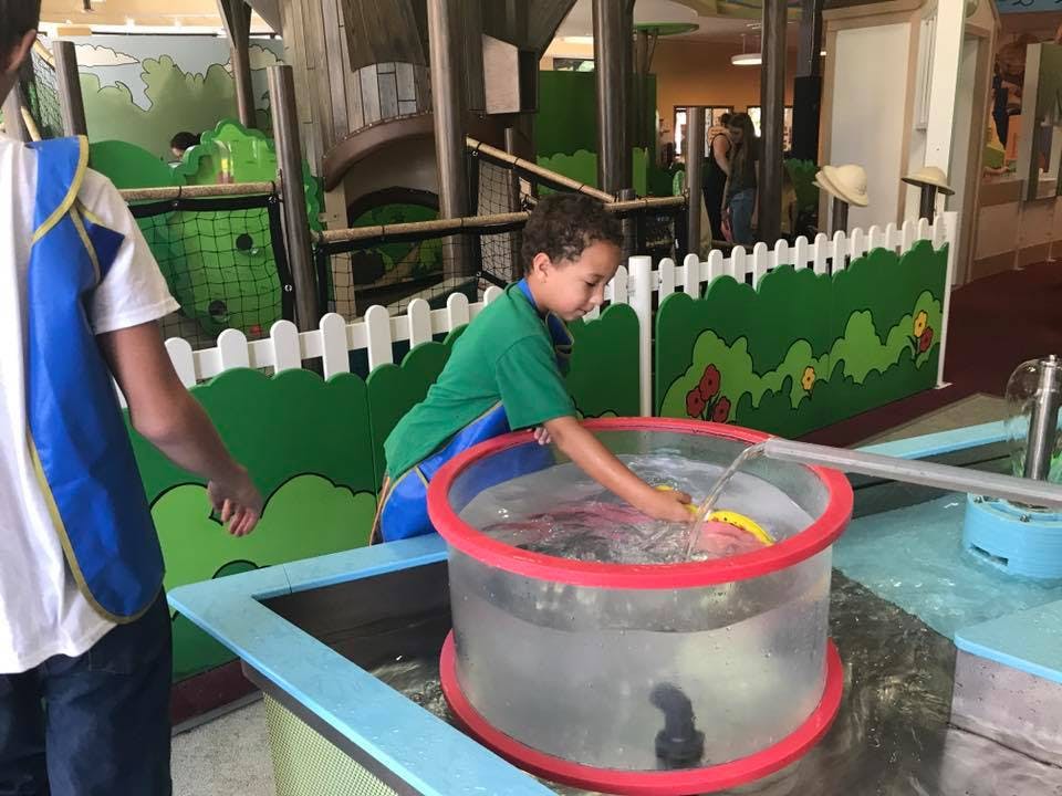 Child playing with water in a clear basin