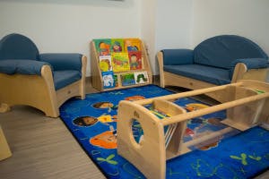 Children's reading nook with small chairs, bookshelf, and rug